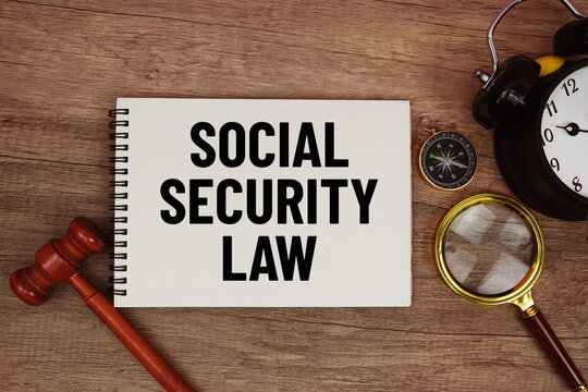 Social Security Law message written on notepad with alarm clock, wood gavel and magnifying glass flat lay on wooden background