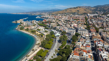 Fototapeta premium Aerial view of Reggio Calabria, a beautiful city overlooking the Mediterranean Sea in southern Italy. It has a long waterfront overlooking the crystal-clear, turquoise sea. It's a sunny summer morning