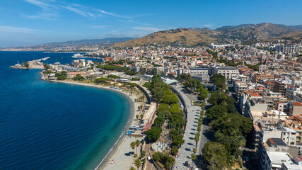 Fototapeta premium Aerial view of Reggio Calabria, a beautiful city overlooking the Mediterranean Sea in southern Italy. It has a long waterfront overlooking the crystal-clear, turquoise sea. It's a sunny summer morning