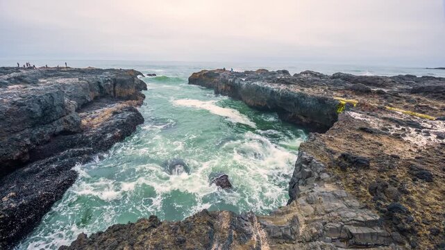 A narrow inlet on the rugged volcanic coastline of the Pacific Ocean at the Cape Perpetua Scenic Area near Yachats, Oregon. Powerful waves rush into the chasm, creating a dramatic, churning effect aga