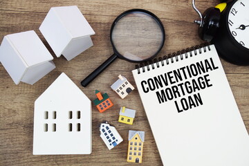 Conventional Mortgage Loan text written on notepad with house model, magnifying glass and alarm clock on wooden background