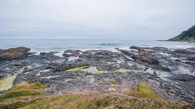 Scenic footage of the rugged, rocky coastline at Cape Perpetua, Oregon, featuring vibrant green tide pools, crashing waves of the Pacific Ocean, and a lush, forested hillside. This area is known for d