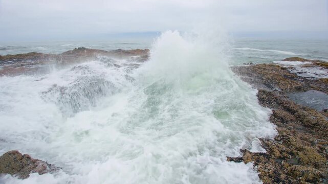 Dramatic photo of Thor's Well, a natural sinkhole and geological formation on the basalt shoreline near Cape Perpetua, Oregon. Seawater powerfully churns and spouts as waves crash into the partially c