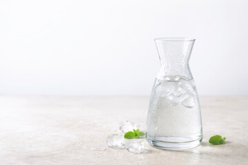 Glass Carafe With Ice Water On Stone Countertop.
Cold water in glass carafe with condensation on beige stone surface and copy space, showing clean hydration and minimalist wellness refresh concept.