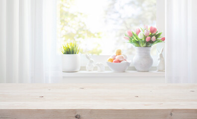 Empty wooden table on blurred background of window sill with Easter tulip flowers, decorative...