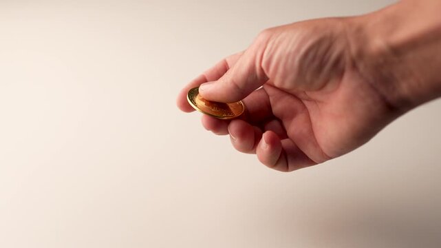 A man's hand plays with a gold bitcoin coin, spinning it on a white surface. Concept of financial gains. Virtual economy and cryptocurrency. Cryptoeconomics. slow motion 4k, 50 fps