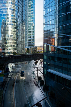 Urban architecture street traffic urban canyon glass Paris La Defense office modern towers lining a wet road with depth and commute energy