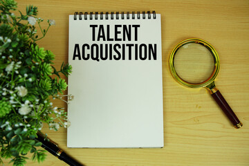 Talent Acquisition text written on notepad with magnifying glass flat lay on wooden background