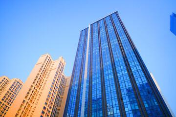 Fototapeta premium Skyscrapers in bright glass exteriors sunlight on sunset. Modern facade office buildings. High-rise bank building in China. Glass facade hotel skyscraper building. Skyscraper modern architecture.