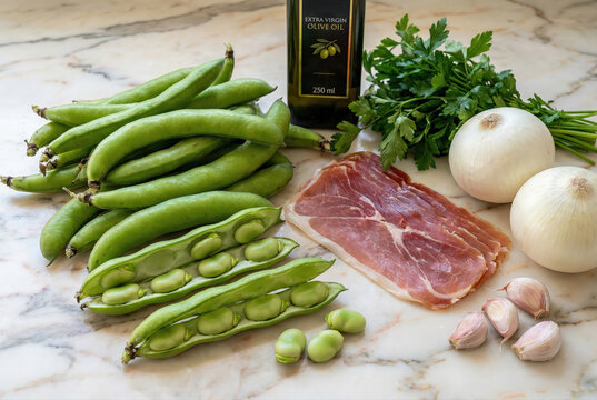 Bodeg&oacute;n de ingredientes frescos para preparar habas con jam&oacute;n: habas verdes en vaina, jam&oacute;n serrano, cebollas, ajo, perejil y aceite de oliva virgen extra