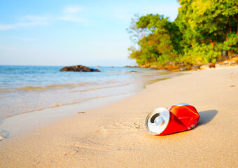 Obraz premium Crumpled soda can on sand beach at sea. Discarded broken soda can at seashore. Environmental pollution, sea water pollution. Rubbish on beach. Clean beach from trash. Empty crumpled can from drink.