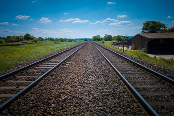 Railway tracks to infinity point, near Tiverton Parkway in Devon on approach to Exeter St Davids under a beautiful blue summer sky