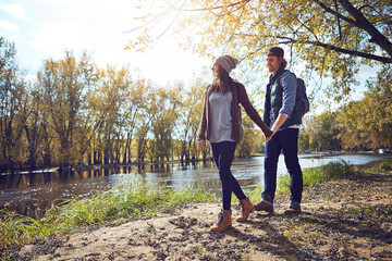 Obraz premium Couple, walk and holding hands on hike, forest and happy with partner in nature, trekking and travel. Outdoor, hikers and people on journey in woods, backpacking and exploration on holiday or trip