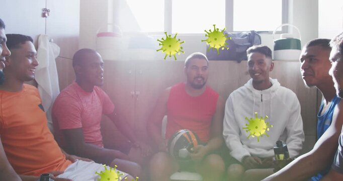 Animation of covid-19 cells icons over team of diverse male soccer players discussing in locker room
