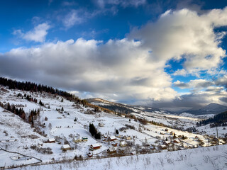 Mystical snowy Carpathian peaks under cloudy skies in the sunny weather