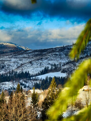 Mystical snowy Carpathian peaks under cloudy skies in the sunny weather