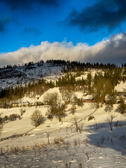 Mystical snowy Carpathian peaks under cloudy skies in the sunny weather