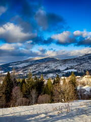 Mystical snowy Carpathian peaks under cloudy skies in the sunny weather