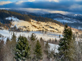Mystical snowy Carpathian peaks under cloudy skies in the sunny weather