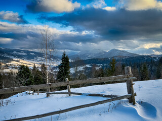 Mystical snowy Carpathian peaks under cloudy skies in the sunny weather
