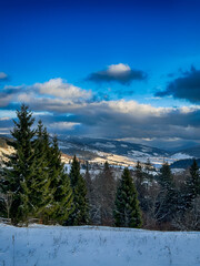 Mystical snowy Carpathian peaks under cloudy skies in the sunny weather