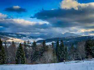 Mystical snowy Carpathian peaks under cloudy skies in the sunny weather