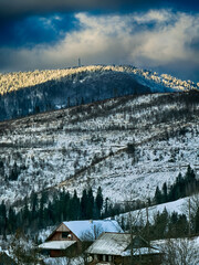 Mystical snowy Carpathian peaks under cloudy skies in the sunny weather