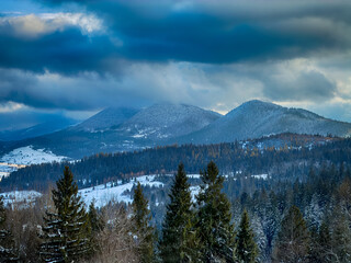 Mystical snowy Carpathian peaks under cloudy skies in the sunny weather