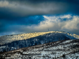 Mystical snowy Carpathian peaks under cloudy skies in the sunny weather