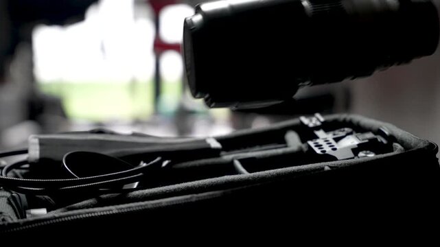 A photographer's hand grips a telephoto lens inside a camera bag, ready for an indoor shoot.