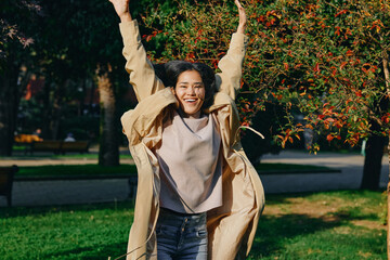 Joy, happiness, girl outdoors, coat, autumn, park, movement, celebration, energy, sunlit scene with...