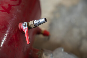 Close-up of red portable air compressor tank safety relief valve and quick coupler fitting mechanism in auto repair garage, Auto repair shop, Garage, Workshop, Pneumatic system, Air compressor