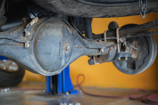Close-up of rusty car rear differential axle housing and leaf spring suspension undercarriage view in auto repair garage, Drive shaft, Oil change, Mechanic workshop, Heavy duty vehicle