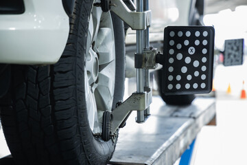 Close-up of 3D wheel alignment target sensor clamped to car alloy wheel for steering and suspension adjustment in auto repair garage, Accuracy Technology Calibration, Car maintenance inspection © Sumala