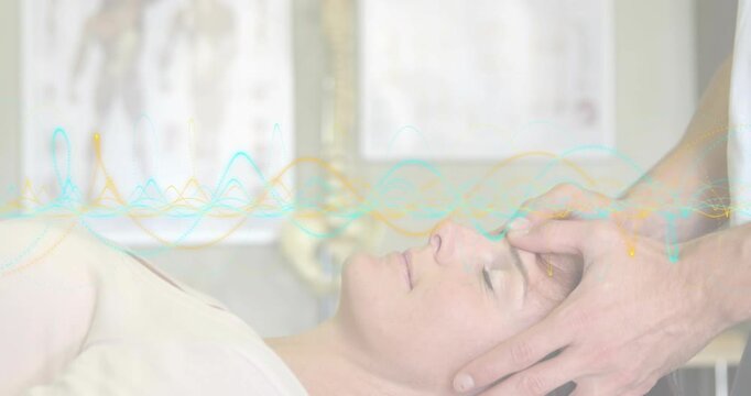 Patient undergoing therapy as therapist placing hands on temples waveforms panning revealing charts