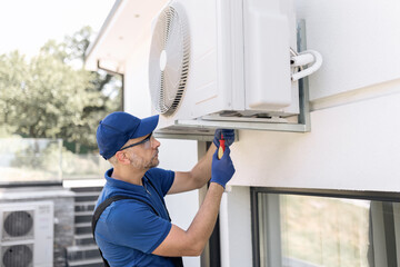 Repairman fixing AC outdoor unit.