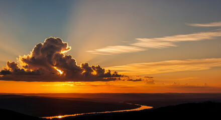 Scenic image of sunset, cumulus cloud, and river winding through terrain, displaying warmth and tranquility, representing natural beauty, peace