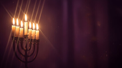 A lit menorah with warm glowing candles on a dark background