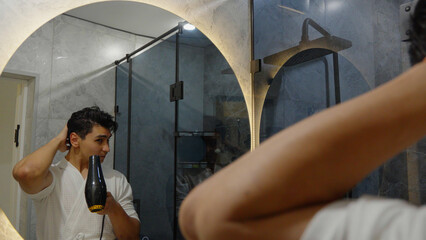 Man styling his hair in front of a mirror at home