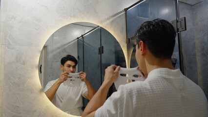 Young man looking in a round mirror in the bathroom