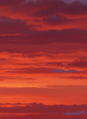 Red and orange sky with dramatic painted clouds at sunset or sunrise. Beautiful vibrant atmospheric background for nature concept.