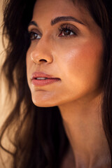 Fototapeta premium Close-up portrait of a woman with long dark hair, showcasing natural beauty and soft lighting, emphasizing facial features and serene expression in a calm atmosphere