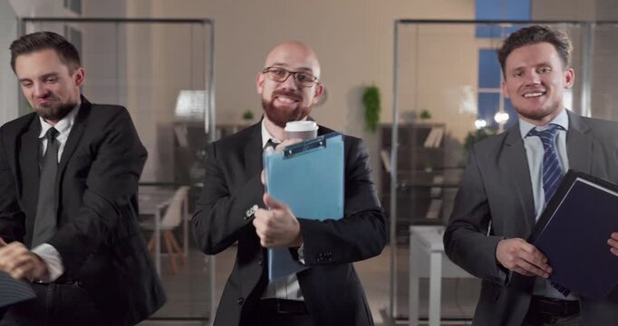 Businessmen dancing in office as cheerful team. Three coworkers in suits perform funny moves at a celebration of success, boosting morale and culture. Concept portrays fun corporate teamwork.