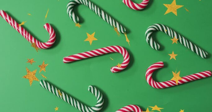 Animation of golden star icons falling over close up of candy cane on green surface