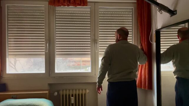 Persona subiendo la persiana de la habitaci&oacute;n con la luz del d&iacute;a al desperar por la ma&ntilde;ana