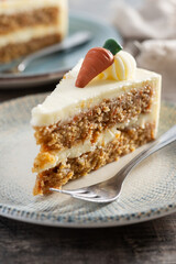 Carrot cake slice with cream cheese frosting on wooden table