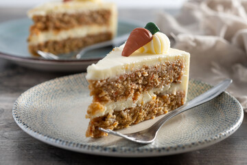 Carrot cake slice with cream cheese frosting on wooden table