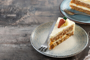 Carrot cake slice with cream cheese frosting on wooden table. Copy space