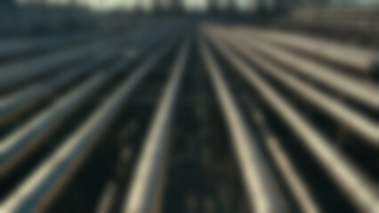 Blurred background of Oil refinery pipes crossing overhead in repeating patterns, metallic textures and shadows, industrial corridor background, morning, soft directional sunlight.