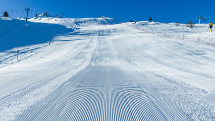 Aerial view of an active ski resort with groomed slopes, chairlifts, and skiers, showcasing winter sports infrastructure and alpine tourism in bright conditions